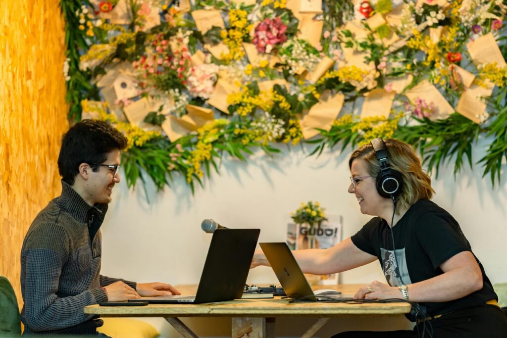 Two people recording a podcast in a stylish Luxembourg studio with floral decor.